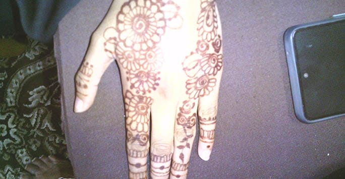 Henna tattoo on hand, close-up of intricate floral and geometric patterns, traditional body art reflecting cultural practices related to ethnicity and age.