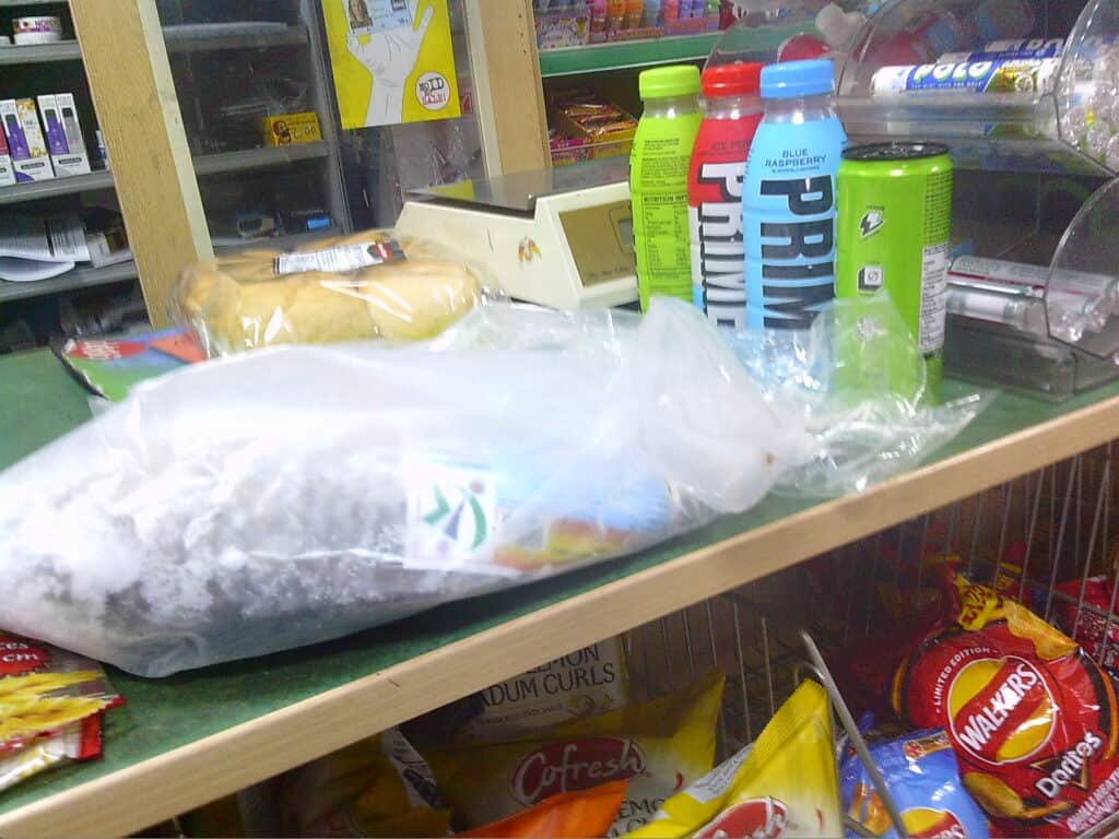 Disposable plastic bag containing grocery items on supermarket checkout counter.