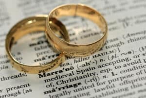 Rings placed on a dictionary page with the word "marriage" highlighted, symbolising relationships and commitments relevant to frailty and ethnicity discussions.