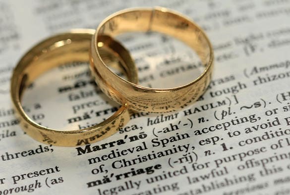 Rings placed on a dictionary page with the word "marriage" highlighted, symbolising relationships and commitments relevant to frailty and ethnicity discussions.