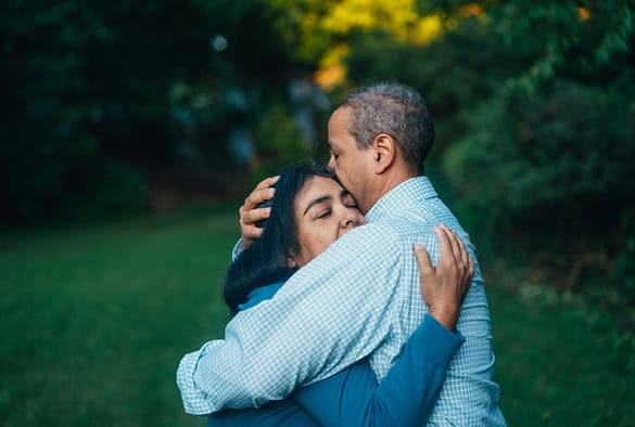 Healthy older couple embracing outdoors, symbolising care and support for frailty and ethnicity in aging.